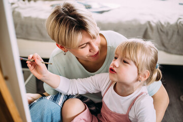 Wall Mural - beautiful mother artist and her child paint picture at home with acrylic paints.