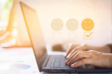 Smart woman using a laptop to choose a happy smiley face icon. Feedback ratings and positive customer review experiences. satisfaction survey mental health assessment world mental health day concept