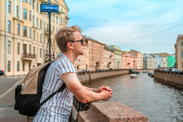 A young man walks through the city center along the canals on a summer day in St. Petersburg