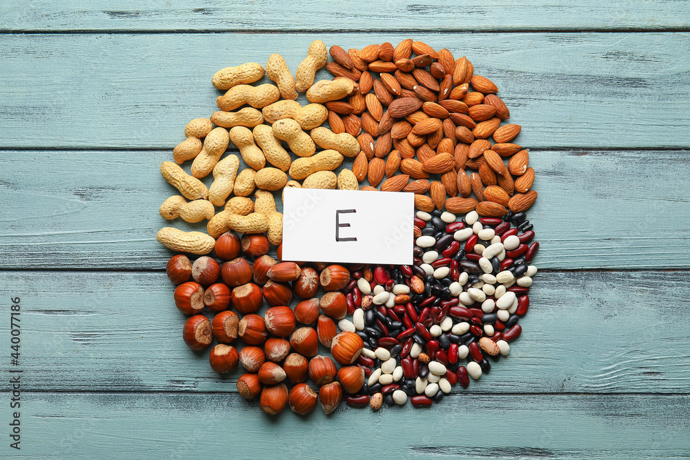 Different healthy nuts and beans rich in vitamin E on color wooden background