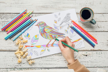 Poster - Woman coloring picture at wooden table, closeup