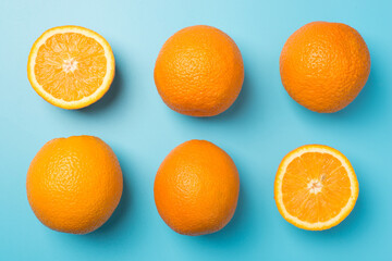 Top view photo of six oranges four whole and two halves in two rows on isolated pastel blue background