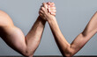 Arm wrestling. Heavily muscled man arm wrestling a puny weak man. Arm wrestling thin hand and a big strong arm in studio. Two man's hands clasped arm wrestling, strong and weak, unequal match