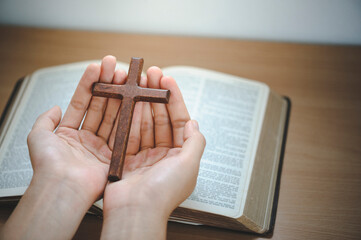 Woman Pray for god blessing to wishing have a better life. hands praying to god with the bible and cross. believe in goodness. Holding hands in prayer on a wooden table.