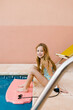 © LIGHTSY STUDIO/Westend61 - Smiling girl sitting at poolside