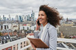 © Annika List/Westend61 - Female entrepreneur with notepad talking on mobile phone in city
