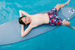© LIGHTSY STUDIO/Westend61 - Boy resting on surfboard in swimming pool