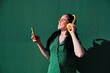 © Alvaro Gonzalez/Westend61 - Woman with vitiligo listening music through headphones by green wall
