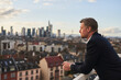 © Annika List/Westend61 - Thoughtful mature businessman standing at rooftop in city