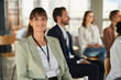 © Annika List/Westend61 - Smiling businesswoman sitting with colleagues at educational event in office