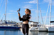 © Albert Mart√≠nez/Westend61 - Beautiful woman photographing holding selfie stick while standing at harbor during sunny day