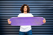 © Antonio Ovejero Diaz/Westend61 - Handsome young man holding skateboard while standing in front of closed shutter