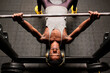 © Antonio Ovejero Diaz/Westend61 - Determined young man doing bench press while listening music through headphones in gym