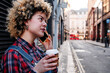© Angel Santana Garcia/Westend61 - Curly haired woman having coffee while talking on smart phone