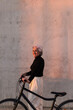 © Picua Estudio/Westend61 - Smiling woman standing with bicycle by wall