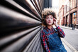 © Angel Santana Garcia/Westend61 - Young woman with hand in hair leaning on corrugated iron