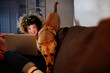 © Angel Santana Garcia/Westend61 - Cheerful young woman using laptop sitting with playful dog at home