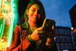 © Angel Santana Garcia/Westend61 - Smiling woman using mobile phone standing by illuminated light