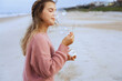 © Arman Zhenikeyev/Westend61 - Portrait of teenage girl blowing soap bubbles on beach