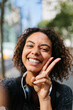 © Boy/Westend61 - Cheerful woman showing peace sign in city