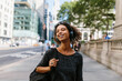 © Boy/Westend61 - Smiling woman looking away while listening music through headphones on footpath in city
