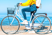 Woman Standing With Bicycle By Sea During Sunny Day