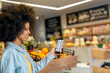 © Emma Innocenti/Westend61 - Afro woman using mobile application in grocery store
