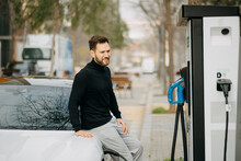 Handsome Man With Car At Electric Vehicle Charging Station