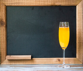 Cocktail drink in front of chalkboard for the drink menu, with tropical wood table