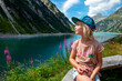 © Anette Christina Gotz/Westend61 - Girl wearing cap looking at view while sitting on wooden bench by lake at Zillertal, Austria