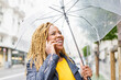 © Ignacio Ferrandiz Roig/Westend61 - Cheerful woman with braided hair talking on phone while holding umbrella
