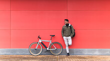 Young Businessman By Bicycle Leaning On Red Wall