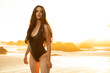 © Ian Spanier/Westend61 - Beautiful model standing in black color swimwear during sunset