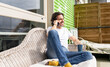 © Jose Carlos Ichiro/Westend61 - Smiling man talking on smart phone while sitting on sofa in balcony