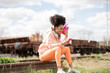 © Jose Carlos Ichiro/Westend61 - Woman with shaker using smart phone while sitting on railway track in shunting yard