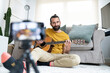 © Jose Carlos Ichiro/Westend61 - Smiling man vlogging while sitting with guitar at home