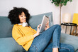 © COROIMAGE/Westend61 - Relaxed young woman using digital tablet while sitting on sofa at home