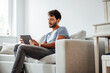 © Joseffson/Westend61 - Young man using digital tablet while sitting on sofa in living room