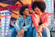 © Julio Rodriguez/Westend61 - Happy female friends talking with each other while sitting in amusement park