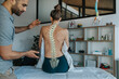 © Infinite Lux/Westend61 - Physiotherapist looking at female patient's bent spine
