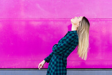 Young Woman With Head Back Standing By Pink Wall