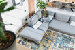 © 27exp/Westend61 - Young woman using laptop while sitting on sofa in living room at home