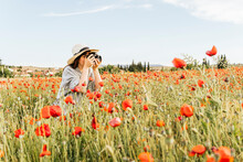 Woman Wearing Hat Photographing With Camera Standing In Poppy Field