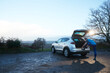 © Pete Muller/Westend61 - Mature runner tying shoelace while leaning on car trunk