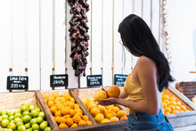 Young Woman With Long Hair Buying Oranges At Grocery Store