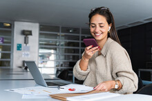 Smiling Businesswoman Sending Voicemail Through Mobile Phone At Office