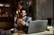 © Rafa Cortes/Westend61 - Happy businessman with laptop holding mobile phone while sitting in coffee shop
