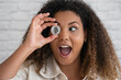 © SERGIO NIEVAS/Westend61 - Excited woman with mouth open covering eye with bitcoin in front of wall