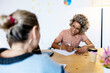 © Rafael Fernandez Torres/Westend61 - Businesswoman discussing with female colleague while writing in book at home office