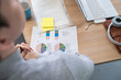 © SERGIO NIEVAS/Westend61 - Young male professional sitting with financial report at desk in office